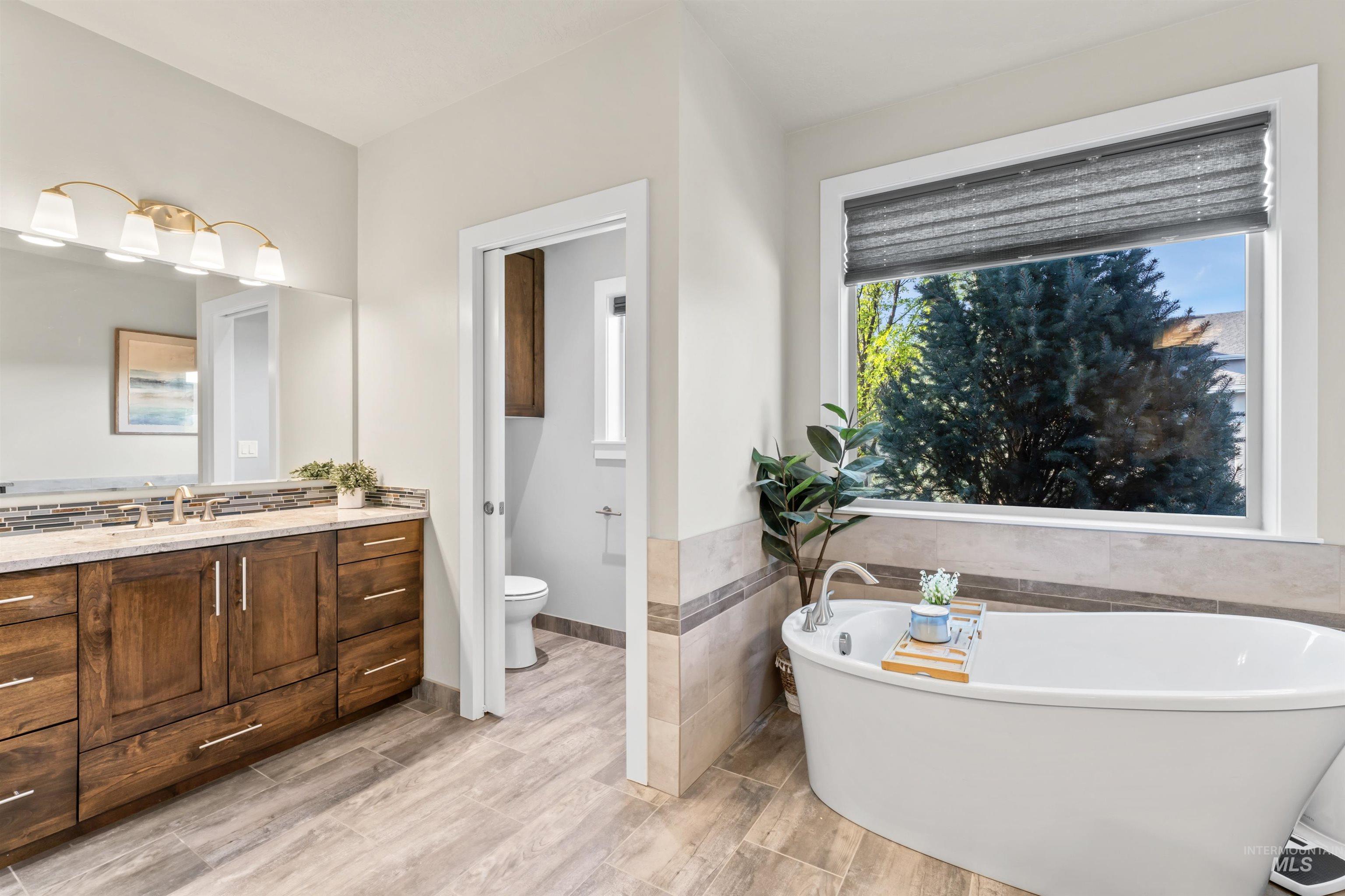 12356 West Rice Road Star, ID 83669 - Photo 22 of 49 Bathroom featuring a freestanding tub, vanity, tile walls, light wood-style flooring, and wainscoting
