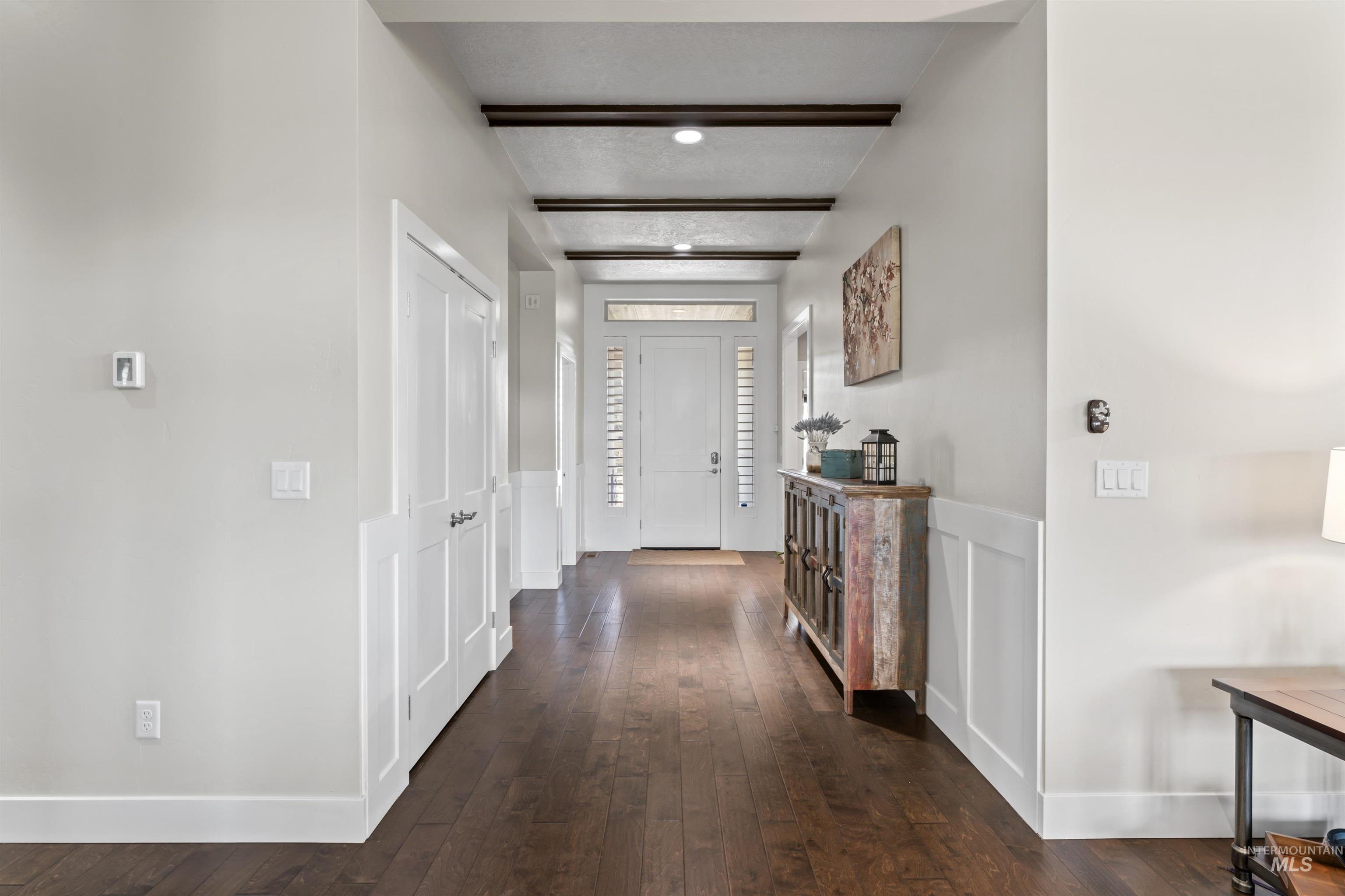12356 West Rice Road Star, ID 83669 - Photo 3 of 49 Hall with dark wood-style floors, a decorative wall, wainscoting, and beamed ceiling