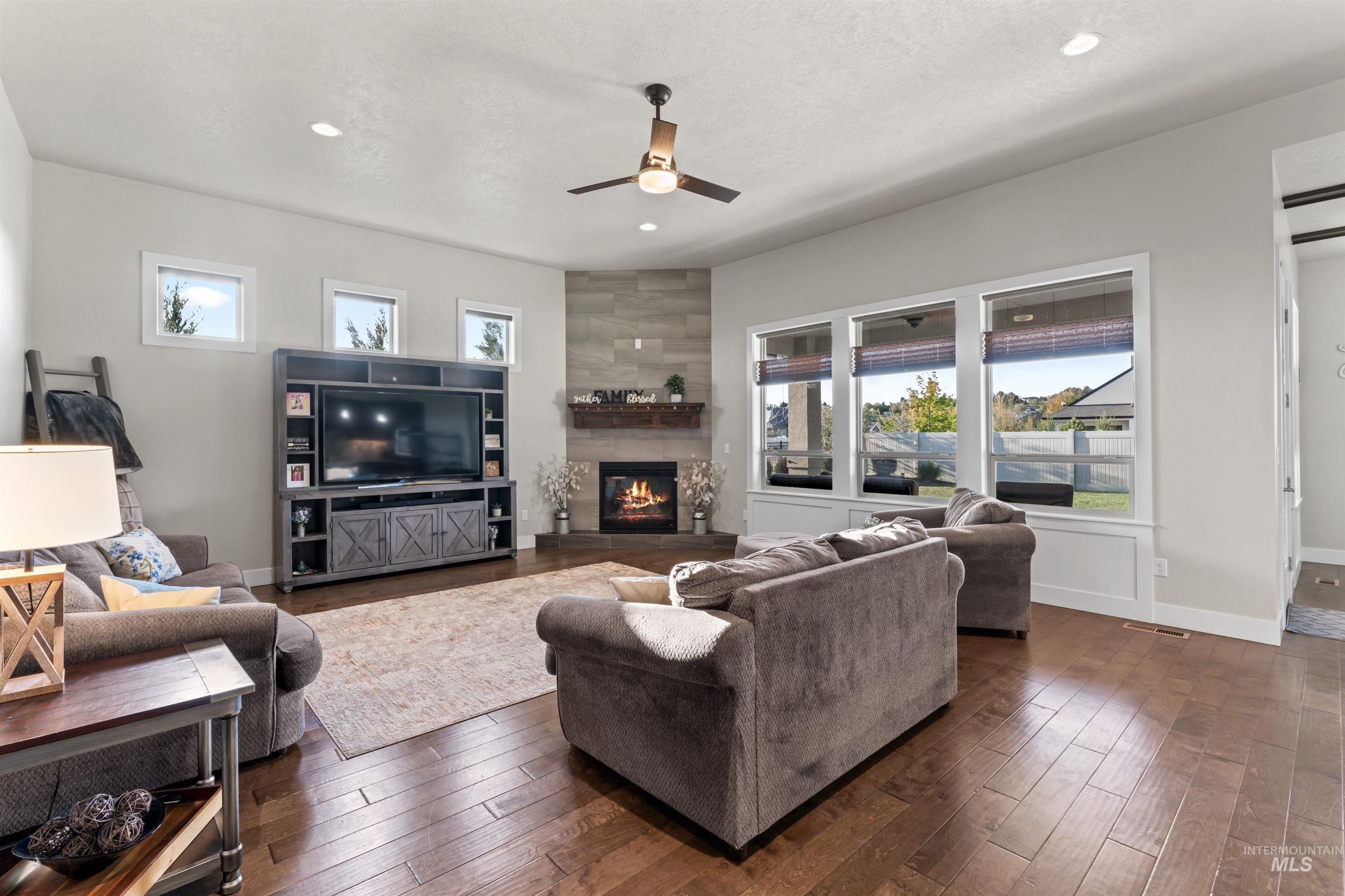 12356 West Rice Road Star, ID 83669 - Photo 5 of 49 Living room featuring dark wood-style floors, a large fireplace, a ceiling fan, and recessed lighting