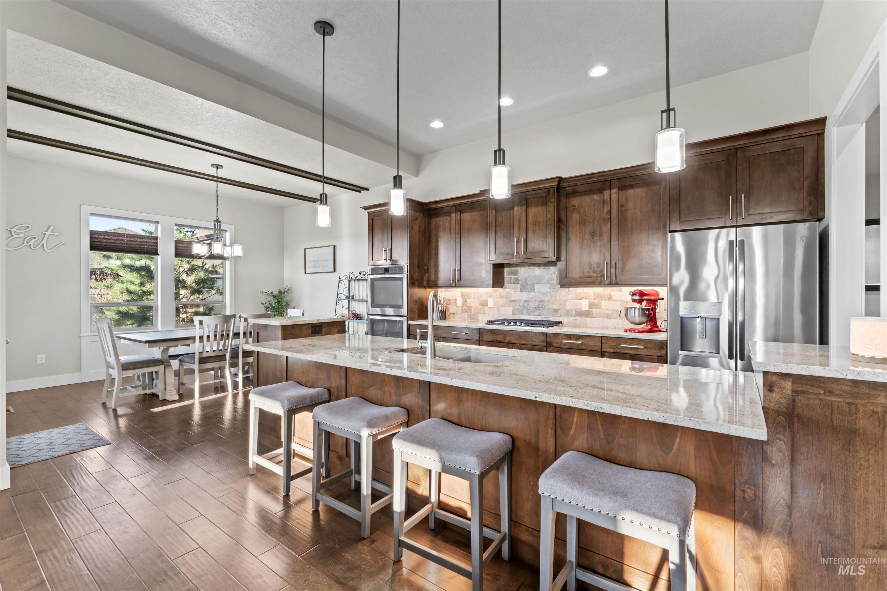 12356 West Rice Road Star, ID 83669 - Photo 7 of 49 Kitchen featuring decorative backsplash, hanging light fixtures, stainless steel appliances, light stone countertops, and recessed lighting