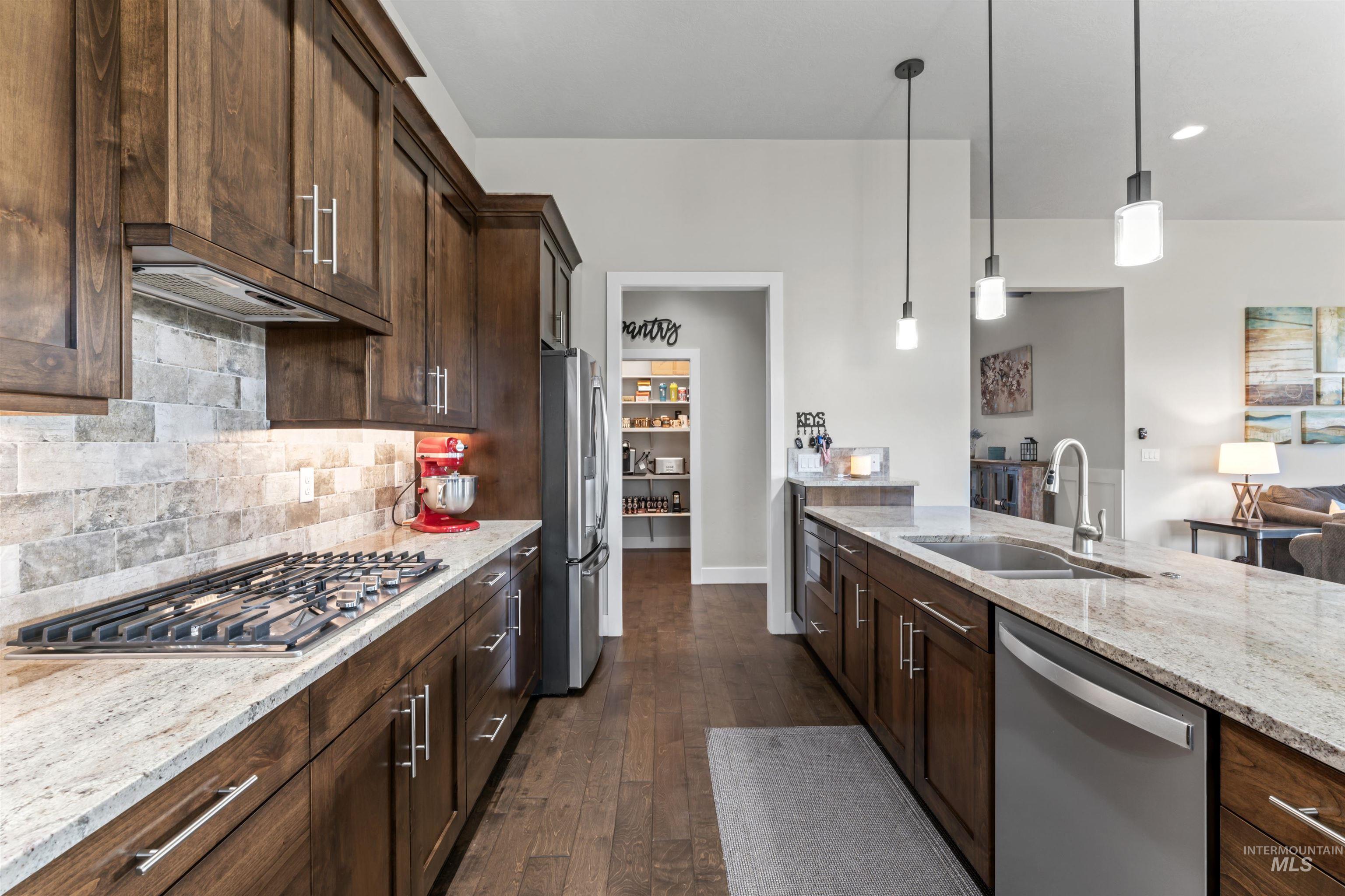 12356 West Rice Road Star, ID 83669 - Photo 10 of 49 Kitchen with light stone counters, dark brown cabinetry, stainless steel appliances, backsplash, and recessed lighting