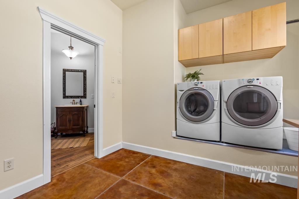 28279 Pearl Road Parma, ID 83660 - Photo 23 of 46 Washroom with dark tile patterned flooring, washer and dryer, and cabinet space