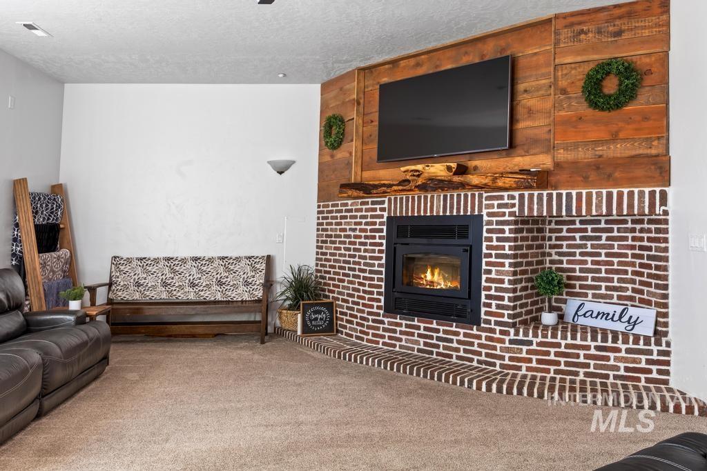 28279 Pearl Road Parma, ID 83660 - Photo 29 of 46 Carpeted living room with a glass covered fireplace and a textured ceiling