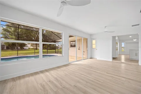 a view of an empty room with a window and wooden floor