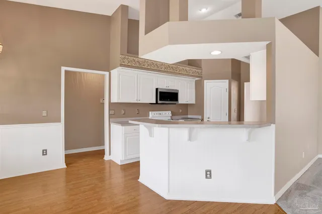 a view of kitchen with stainless steel appliances wooden floor and living room