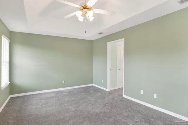 an empty room with a chandelier fan and windows