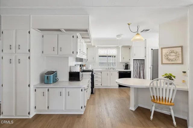 a kitchen with white cabinets and wooden floor