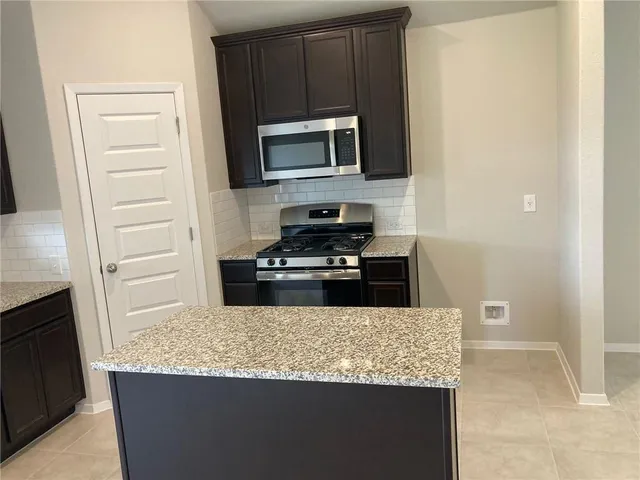 a kitchen with granite countertop a sink and a stove top oven with wooden floor