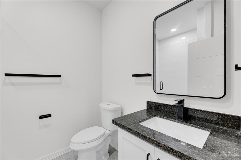 425 South 12th Street Alamo, TX 78516 - Photo 12 of 15 a bathroom with a granite countertop sink a toilet and a mirror