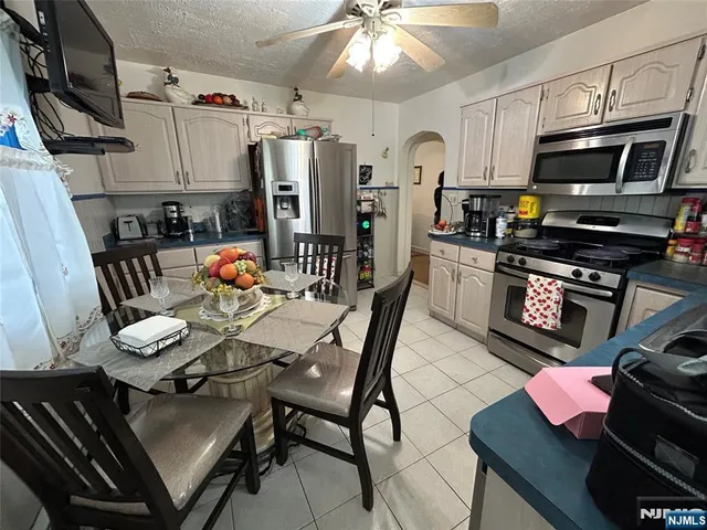 a kitchen with stainless steel appliances a stove a sink dishwasher a dining table and chairs with wooden floor