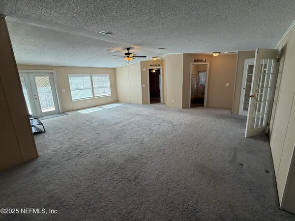 an empty room with windows and chandelier fan