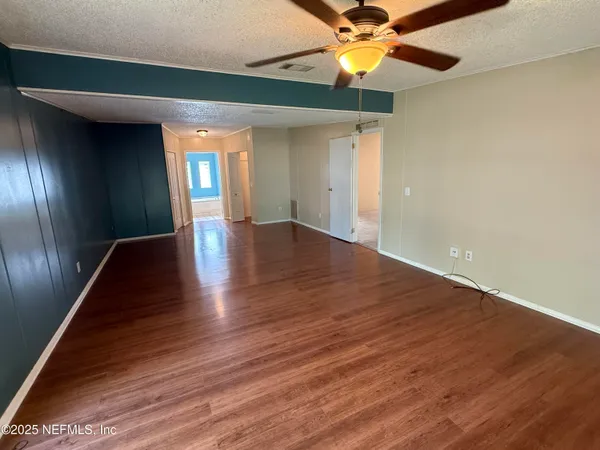 a view of an empty room with window and wooden floor