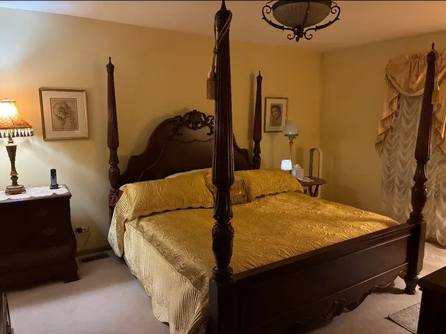 a bed sitting in a bedroom next to a window and a lamp