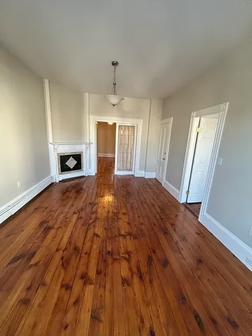 a view of empty room with wooden floor and fireplace
