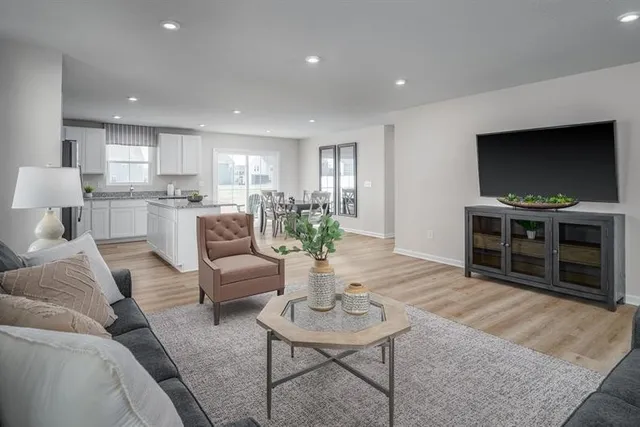 a living room with furniture a flat screen tv and kitchen view