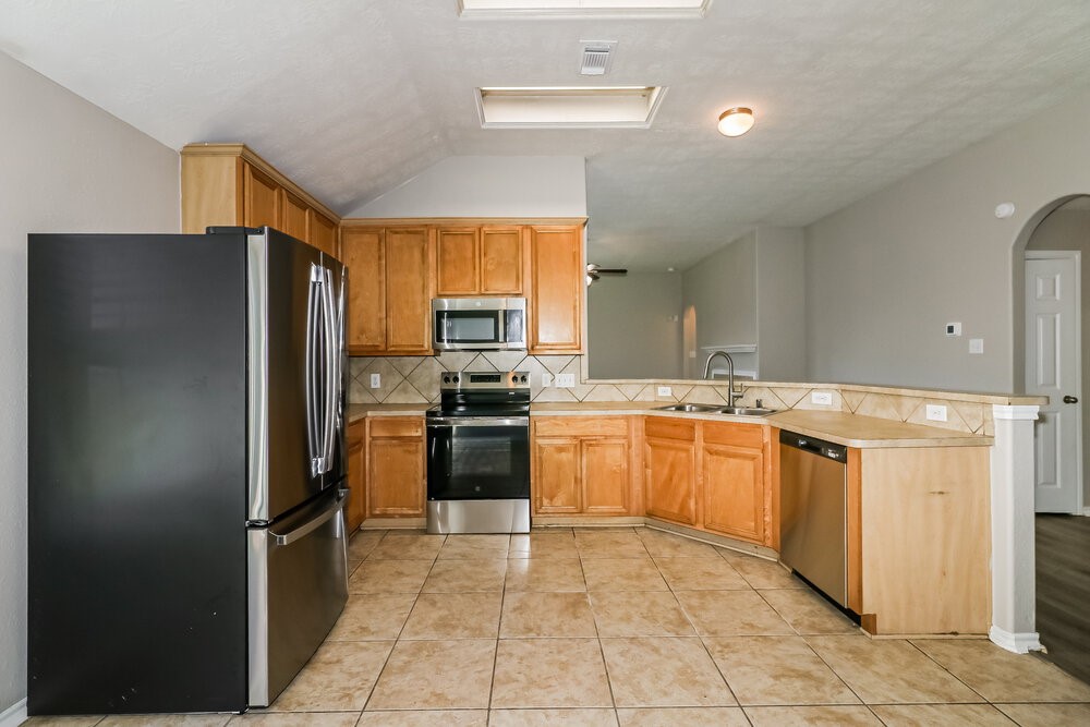 16419 Great Ridge Court Houston, TX 77083 - Photo 6 of 16 a kitchen with stainless steel appliances granite countertop a refrigerator and a sink
