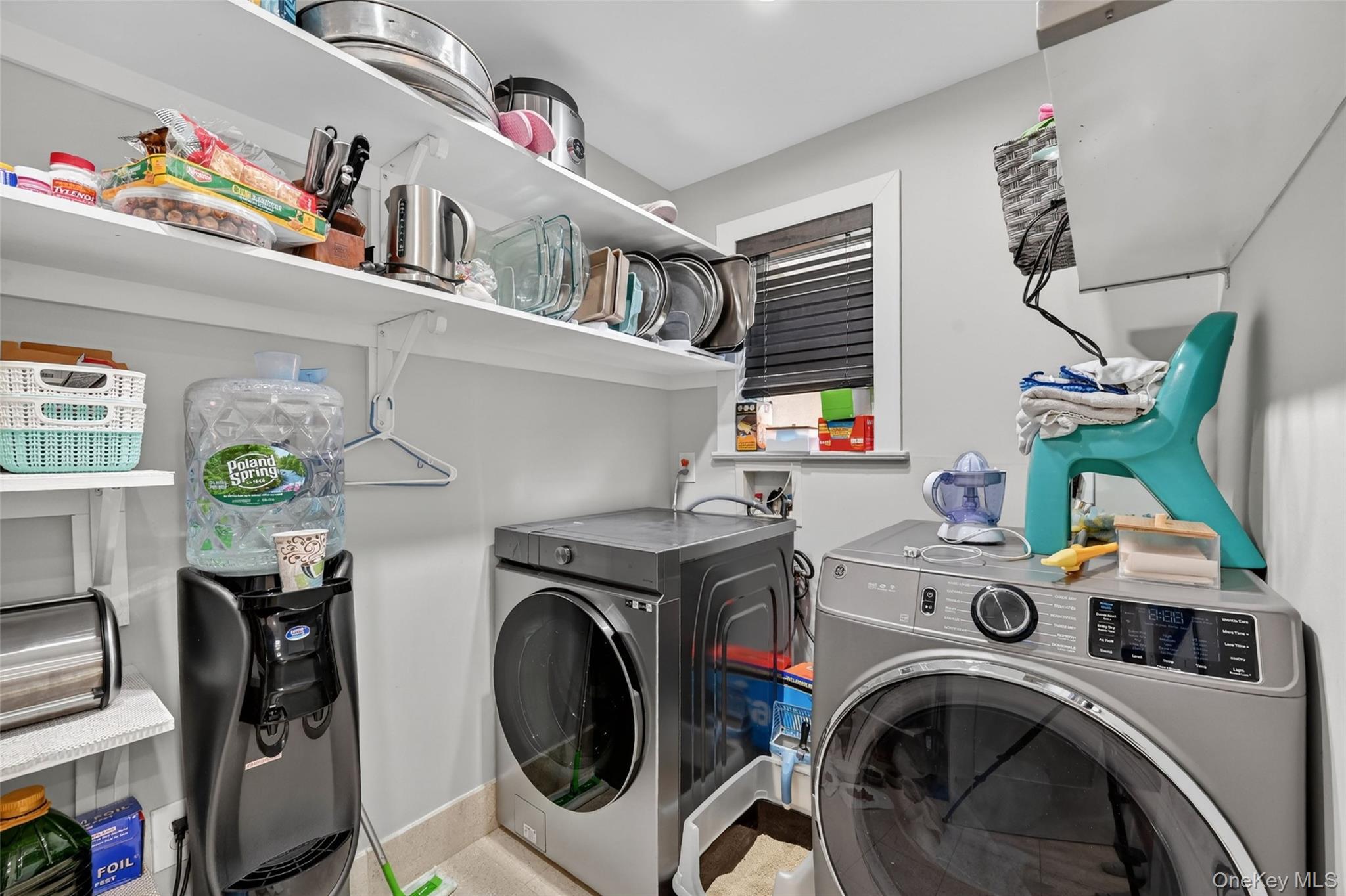 65 Wildway Bronxville, NY 10708 - Photo 34 of 42 Dedicated utility space featuring a front-load washer and dryer, ample shelving for storage, and a single window with blinds
