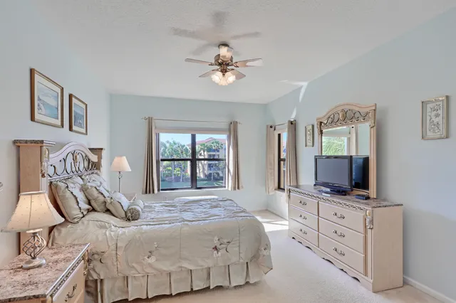 a bedroom with a bed a window a flat screen tv and a dresser