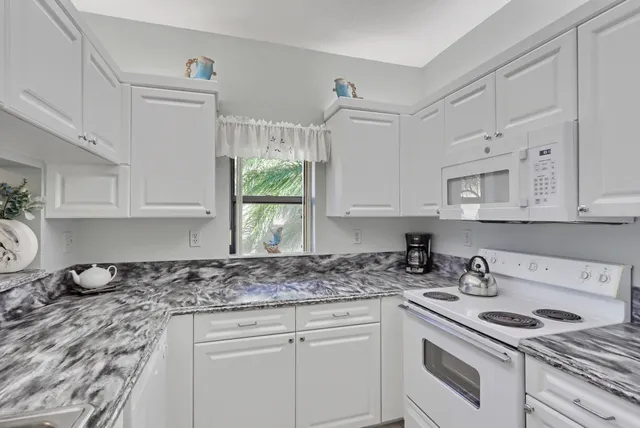 a kitchen with white cabinets and white appliances