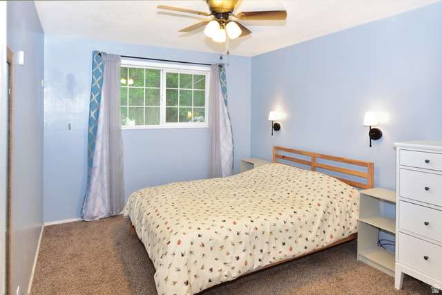 315 Park Street Inkom, ID 83245 - Photo 11 of 28 Bedroom featuring a window with grid panes, a ceiling fan with light kit, twin wall sconces, and carpet flooring