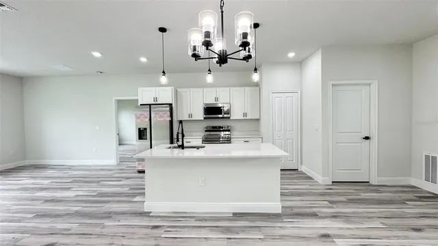 a view of a kitchen with kitchen island stainless steel appliances wooden floor and living room view