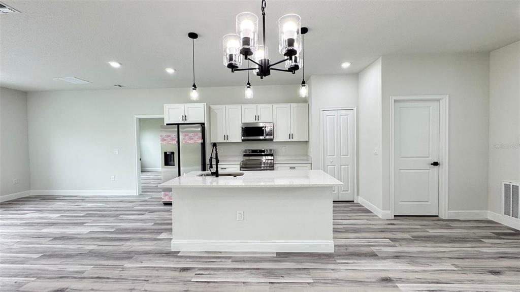 16884 Southwest 39th Circle Ocala, FL 34472 - Photo 4 of 29 a view of a kitchen with kitchen island stainless steel appliances wooden floor and living room view
