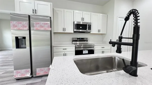 a kitchen with stainless steel appliances kitchen island granite countertop a refrigerator a stove and a sink