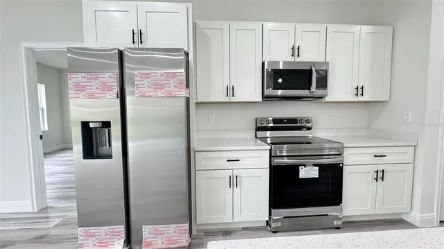 a kitchen with stainless steel appliances granite countertop a stove a refrigerator and a microwave