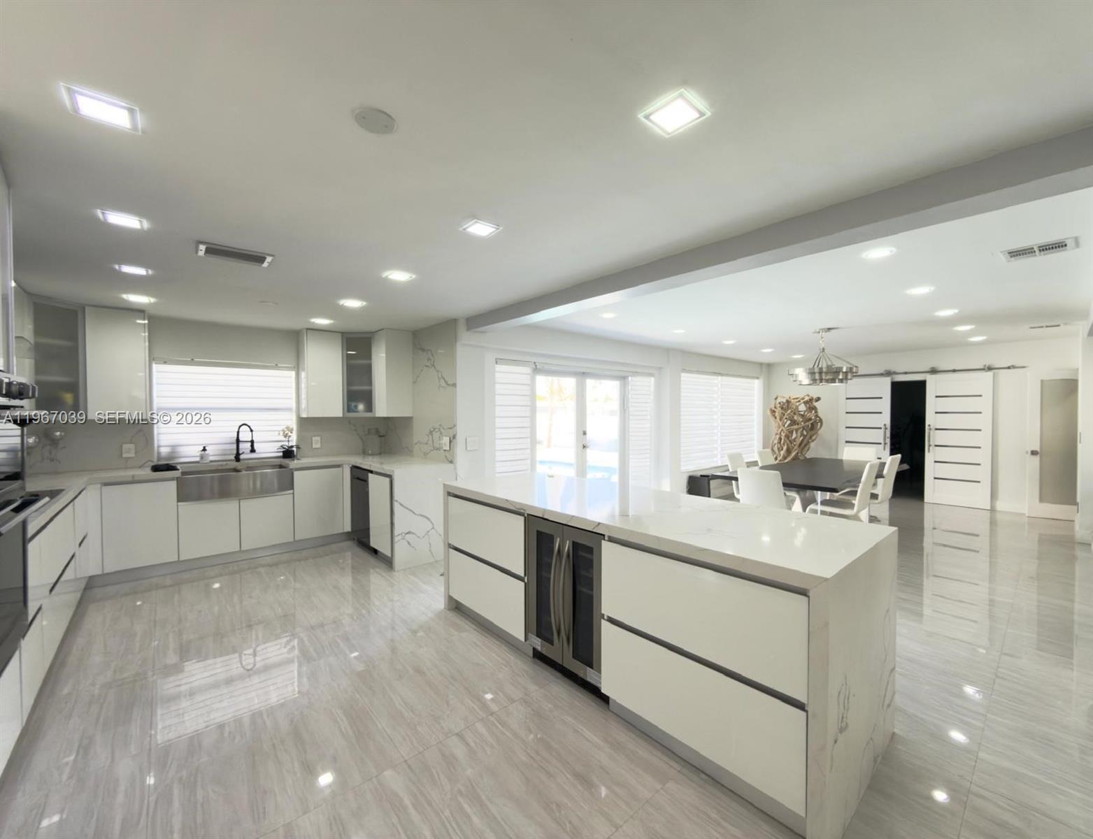 a large white kitchen with a large window and stainless steel appliances