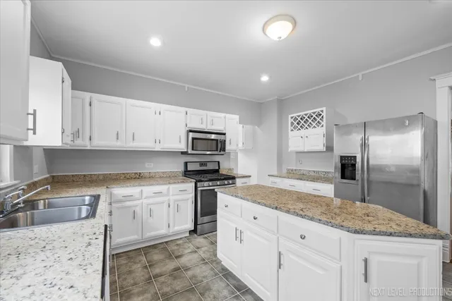 a kitchen with granite countertop a sink stainless steel appliances and white cabinets