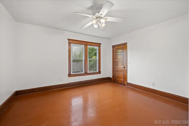 an empty room with windows and ceiling fan