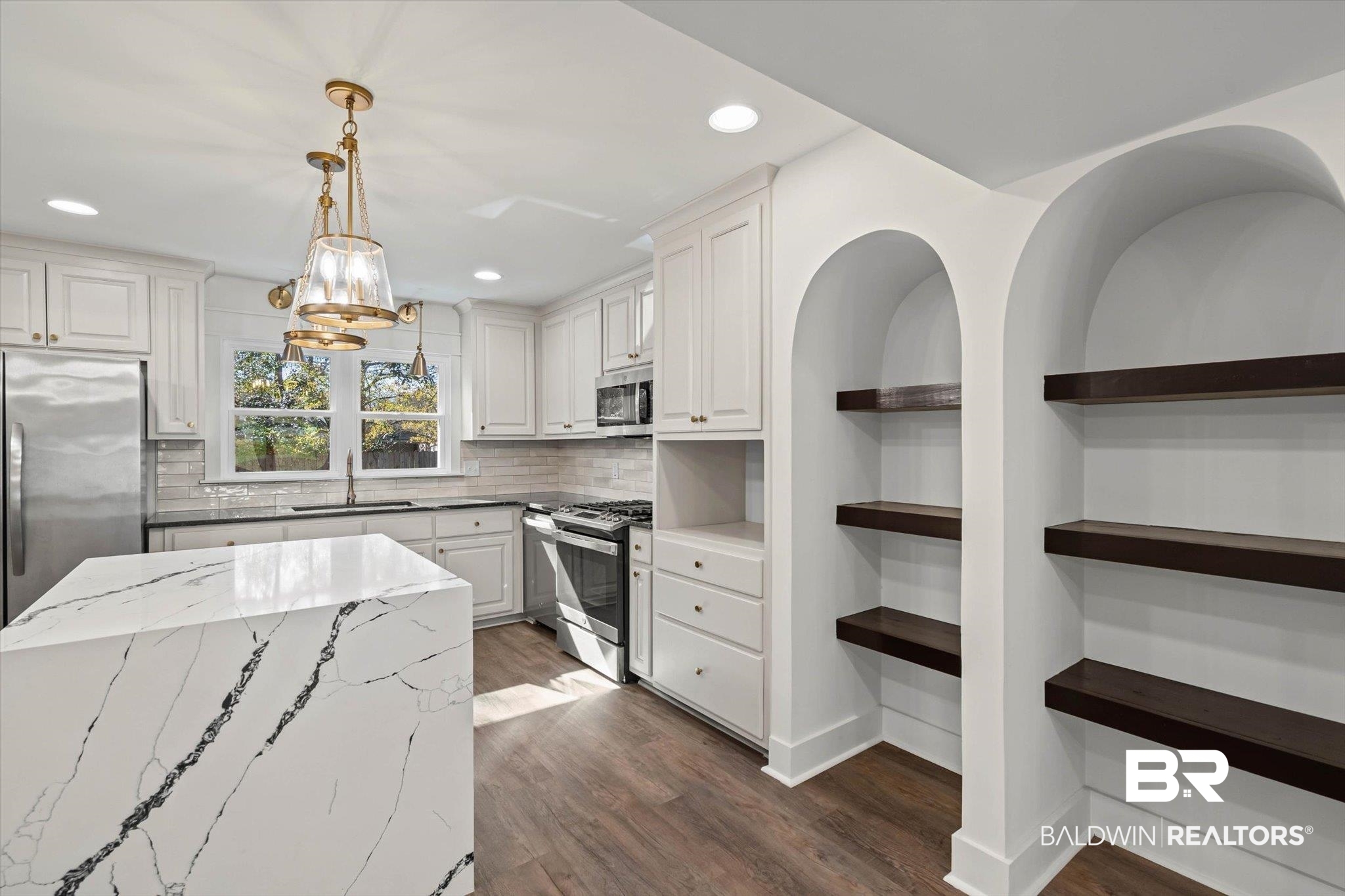 3933 Radnor Avenue Mobile, AL 36608 - Photo 4 of 36 THIS Kitchen! White cabinets, stone countertops reveal nature's beauty, specialty hanging light fixtures, dark wood-style floors, appliances with stainless steel finishes, and tasteful backsplash, recessed lighting ... Arched insets with shelves for ...