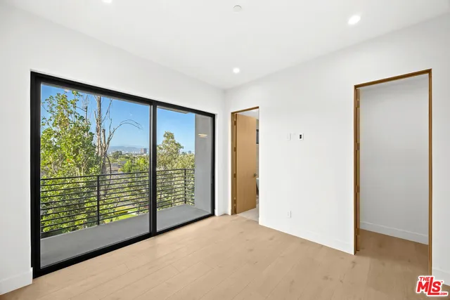 a view of an empty room with wooden floor and a balcony