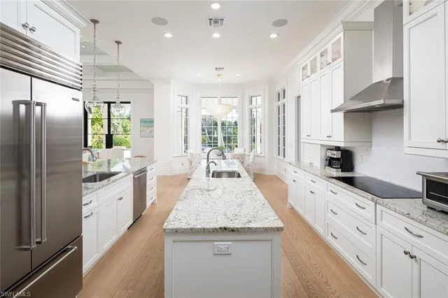 a large kitchen with granite countertop lots of counter space wooden floor and stainless steel appliances