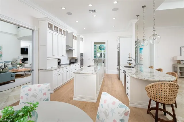 a large white kitchen with a white countertops a stove and a dining table with wooden floor
