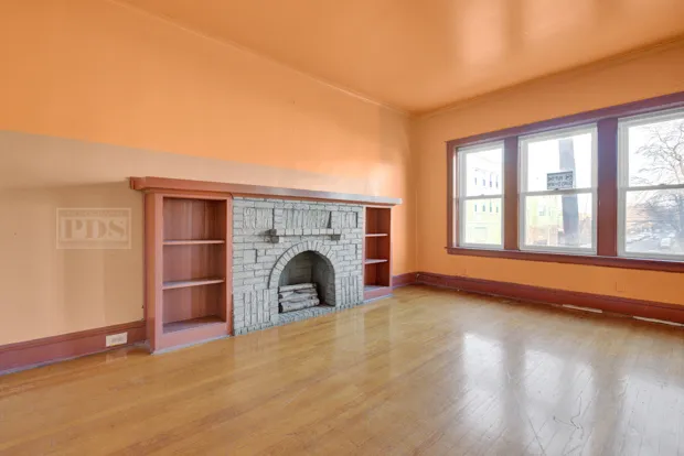 an empty room with fireplace and windows