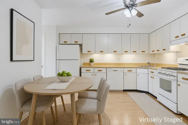 a kitchen with stainless steel appliances a white table chairs and a refrigerator
