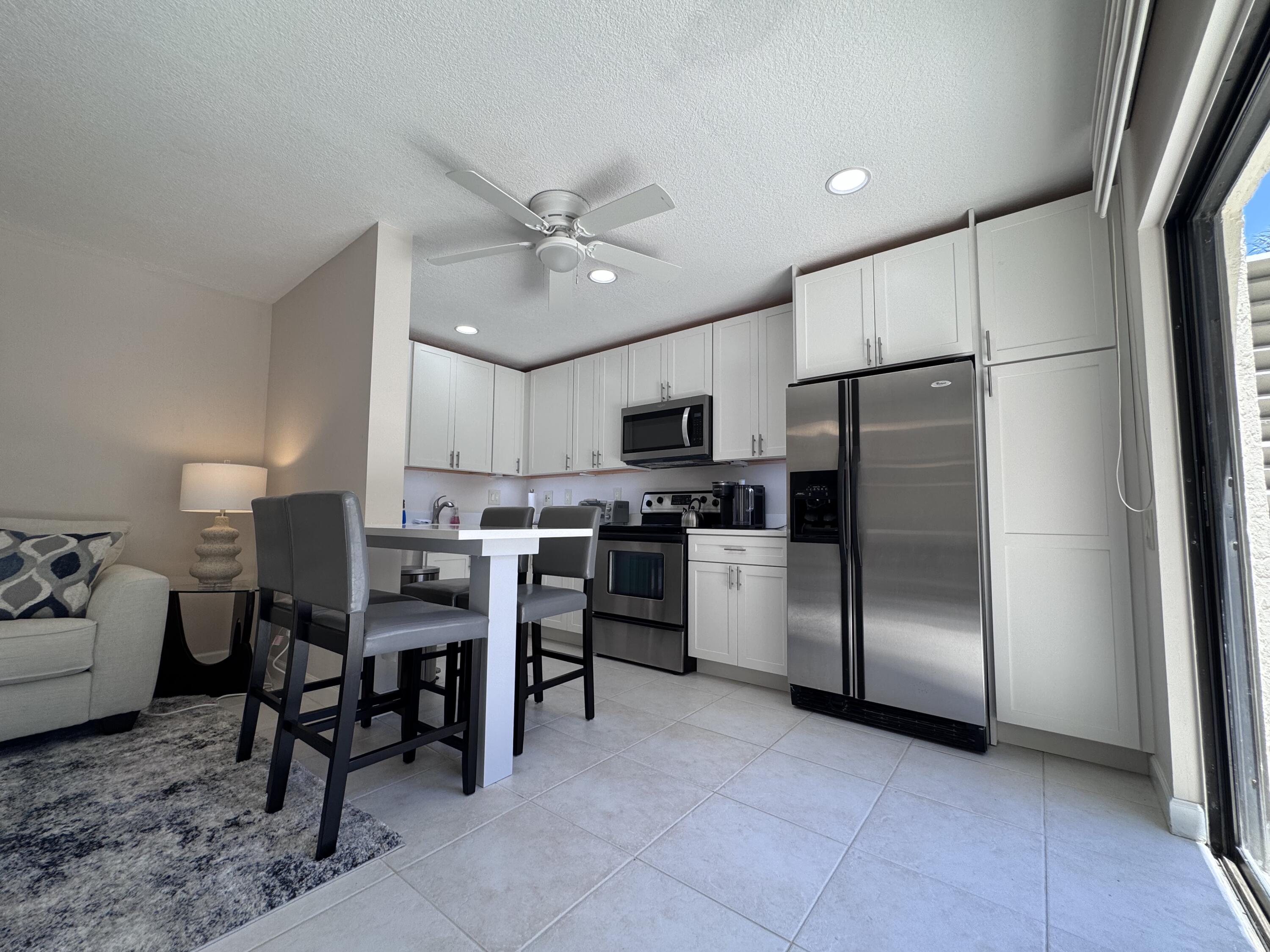 1605 Highway 1, Unit 1A Jupiter, FL 33477 - Photo 5 of 23 a kitchen with stainless steel appliances a refrigerator a stove a sink a dining table and chairs