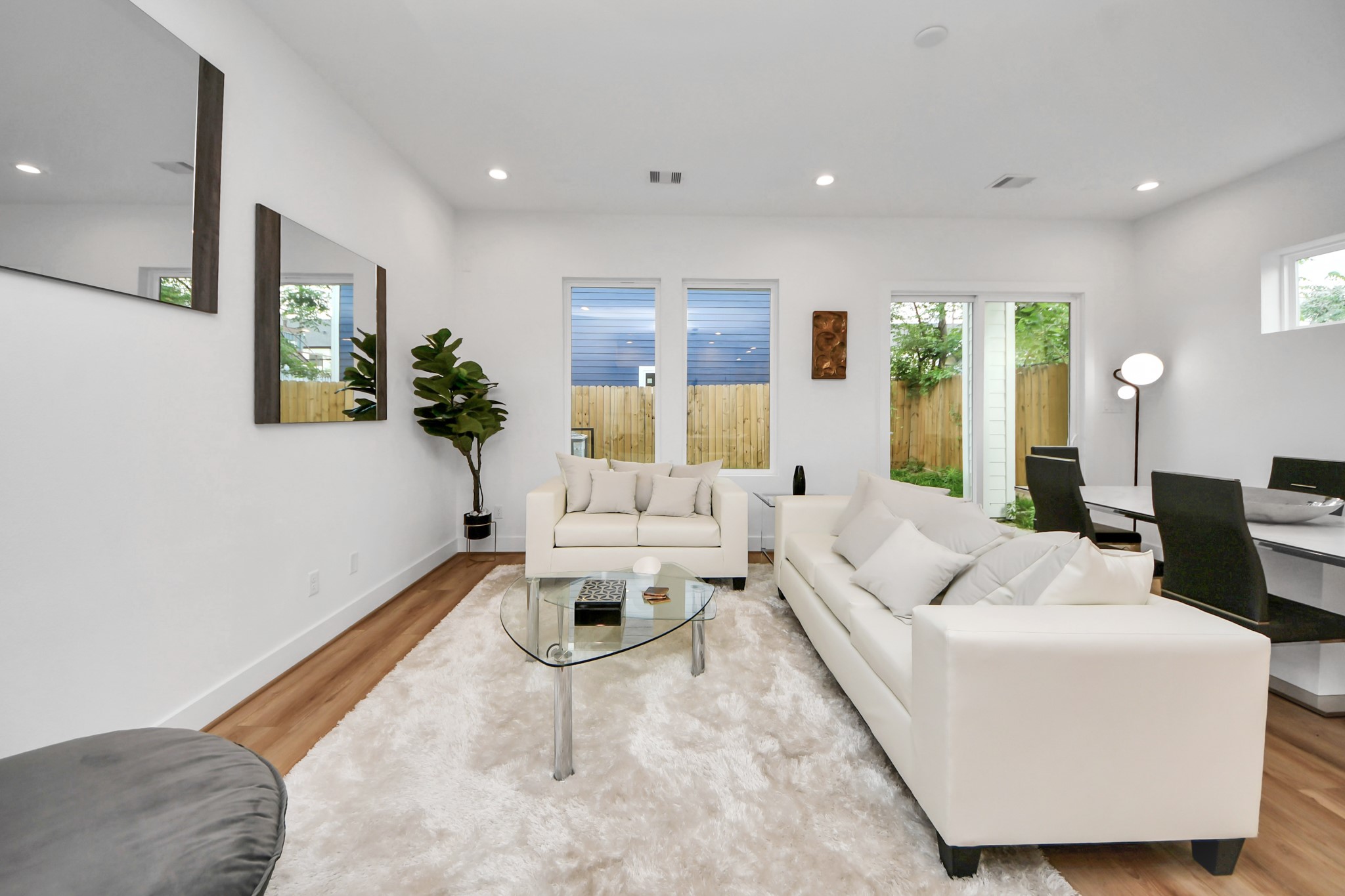 505 Middle Street Houston, TX 77003 - Photo 16 of 46 This inviting living room boasts modern elegance with its bright, open layout, chic white sofas, and warm wooden floors, seamlessly connecting to a serene outdoor space.