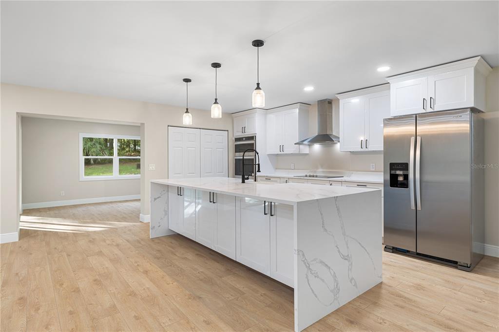 20045 Southwest 88th Place Road Dunnellon, FL 34431 - Photo 5 of 53 a kitchen with kitchen island granite countertop a refrigerator oven a sink dishwasher and white cabinets with wooden floor