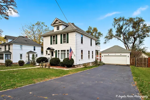 a front view of a house with a garden and trees