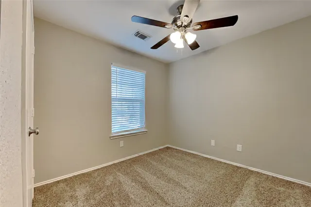 an empty room with a window and a fan