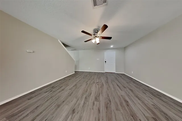 an empty room with wooden floor and ceiling fan