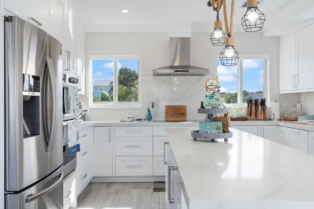 a kitchen with stainless steel appliances a refrigerator a sink a stove and white cabinets