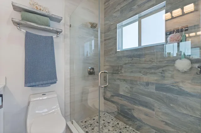 a bathroom with a granite countertop shower a toilet and a sink