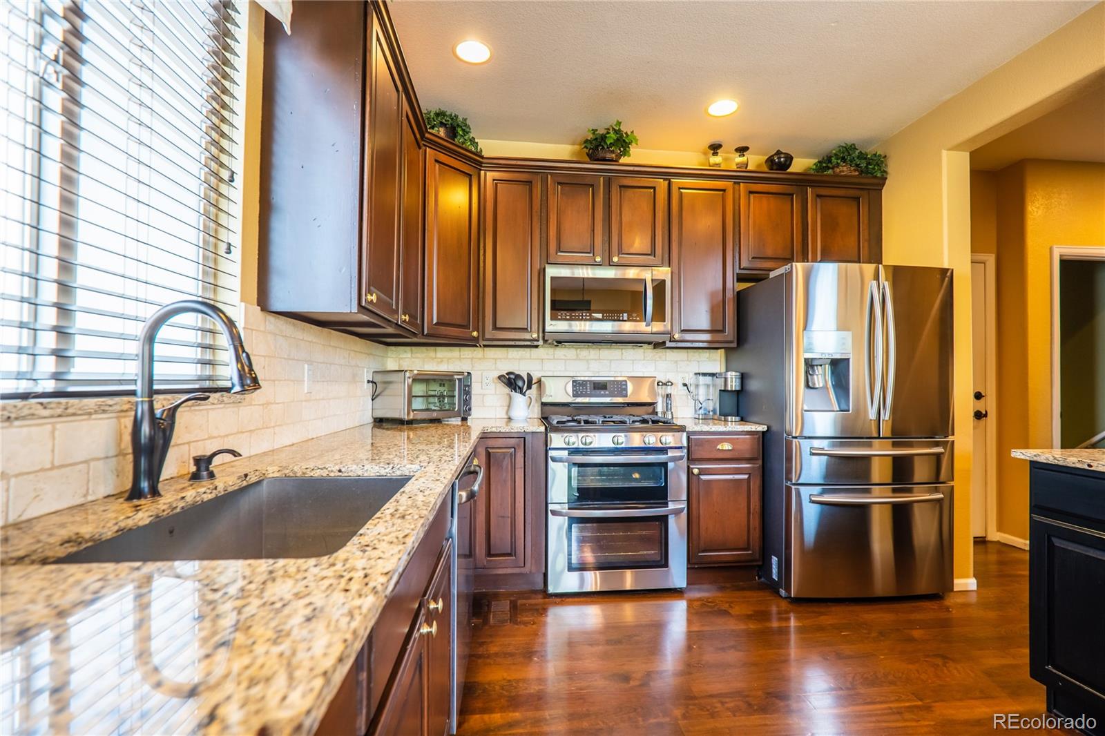 10857 Hickory Ridge Street Highlands Ranch, CO 80126 - Photo 15 of 40 a kitchen with kitchen island granite countertop a sink appliances and cabinets