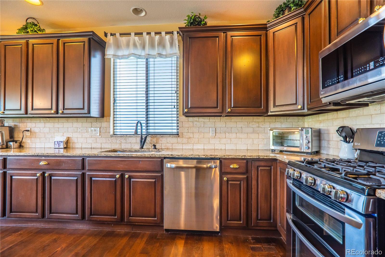 10857 Hickory Ridge Street Highlands Ranch, CO 80126 - Photo 16 of 40 a kitchen with granite countertop wooden cabinets stainless steel appliances and a sink