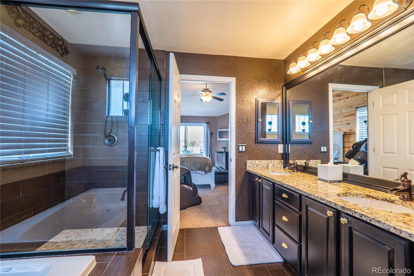 10857 Hickory Ridge Street Highlands Ranch, CO 80126 - Photo 22 of 40 a spacious bathroom with a granite countertop sink a toilet a mirror and shower
