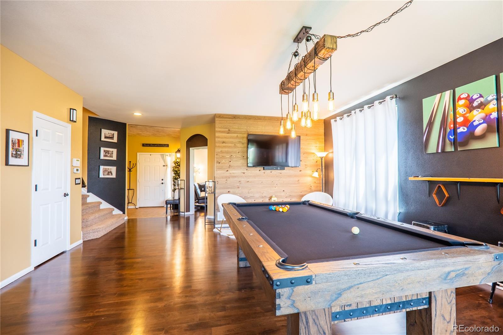 10857 Hickory Ridge Street Highlands Ranch, CO 80126 - Photo 10 of 40 a living room with furniture pool table wooden floor and a floor to ceiling window