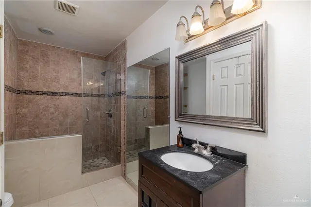 a bathroom with a granite countertop sink a mirror and a shower
